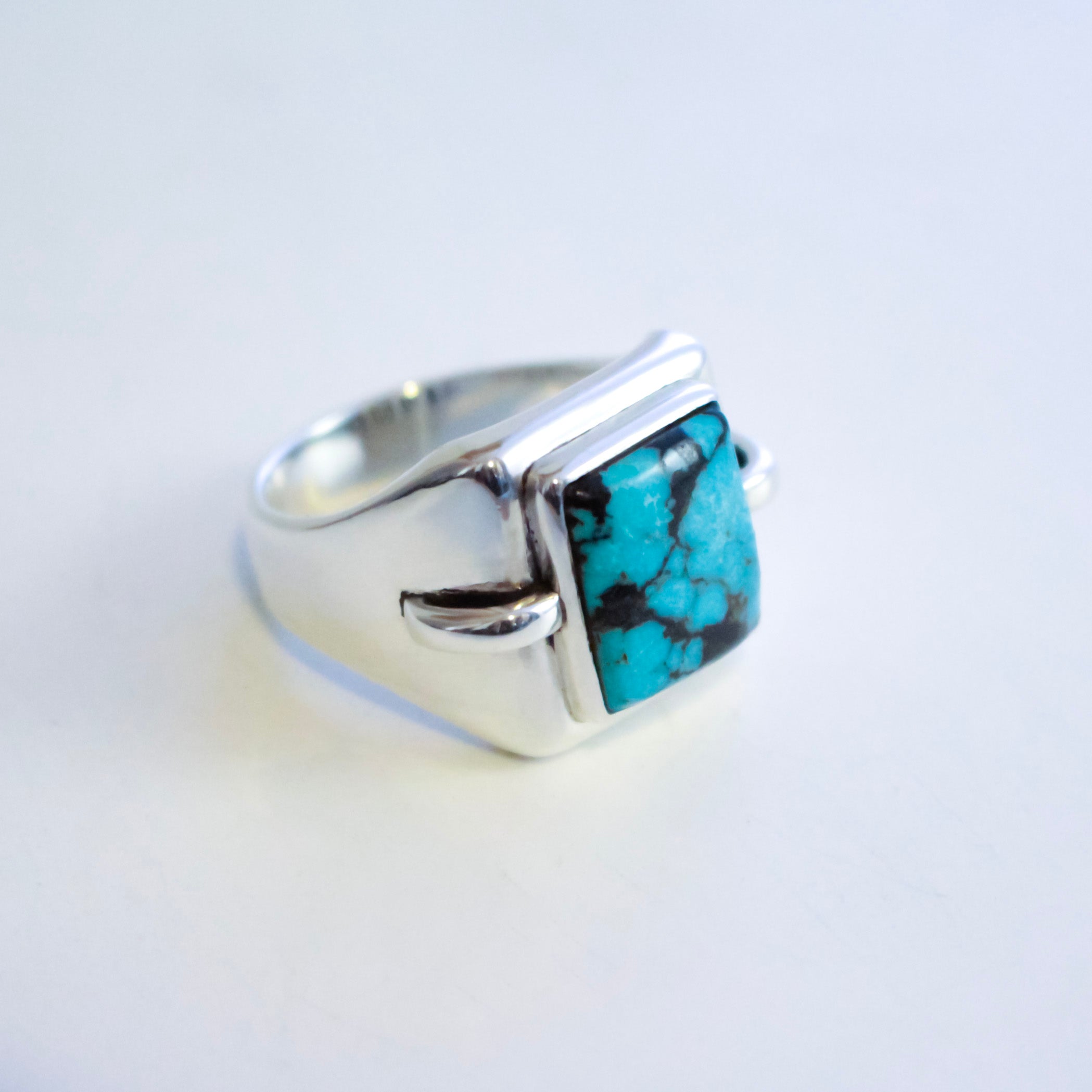 A sterling silver ring featuring a square-cut hubei turquoise stone with natural black veining, set in a modern geometric bezel on a plain white background.