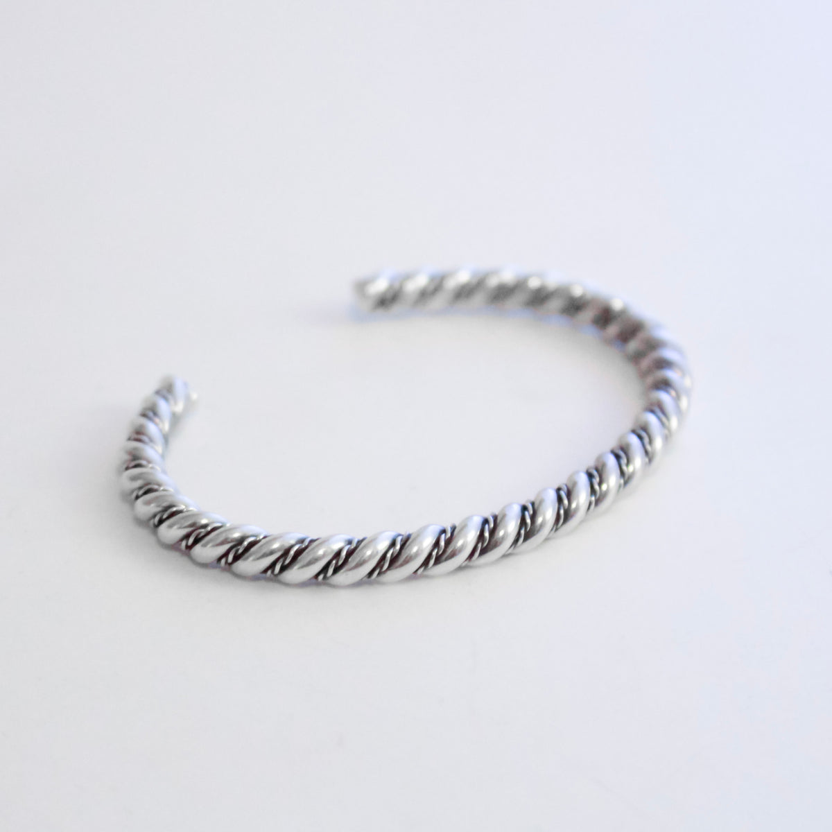 A silver twisted rope cuff bracelet on a plain white background.
