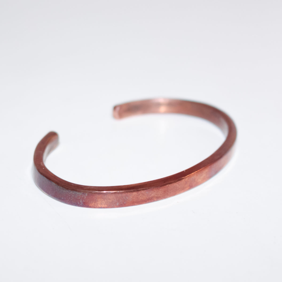 A hammered copper open cuff bracelet on a plain white background.