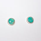 A pair of round stud earrings with turquoise stones set in silver, shown on a plain white background.