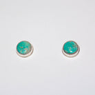 A pair of silver stud earrings with oval turquoise cabochon stones, displayed on a plain white background.