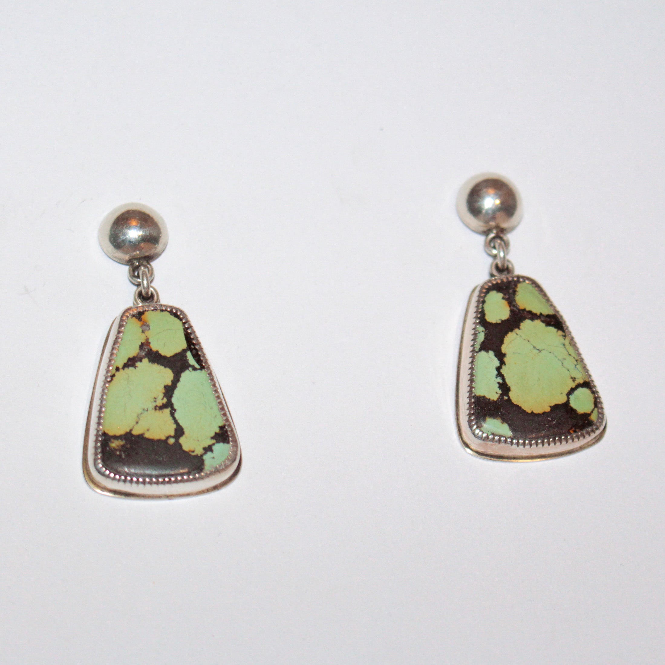 A pair of sterling silver dangle earrings featuring organic-shaped Bao Canyon turquoise stones with light green and dark brown matrix patterns, suspended from round silver studs on a plain white background.