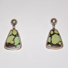 A pair of sterling silver stud earrings featuring irregular triangle-shaped Bao Canyon Turquoise pendants with a dark brown base and light green matrix, set against a plain white background.