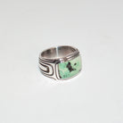 A silver band ring featuring a rectangular green Pixie Turquoise stone with black inclusions, set against a plain white background.