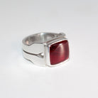 A silver ring with a square, rounded red carnelian, photographed on a plain white background.

