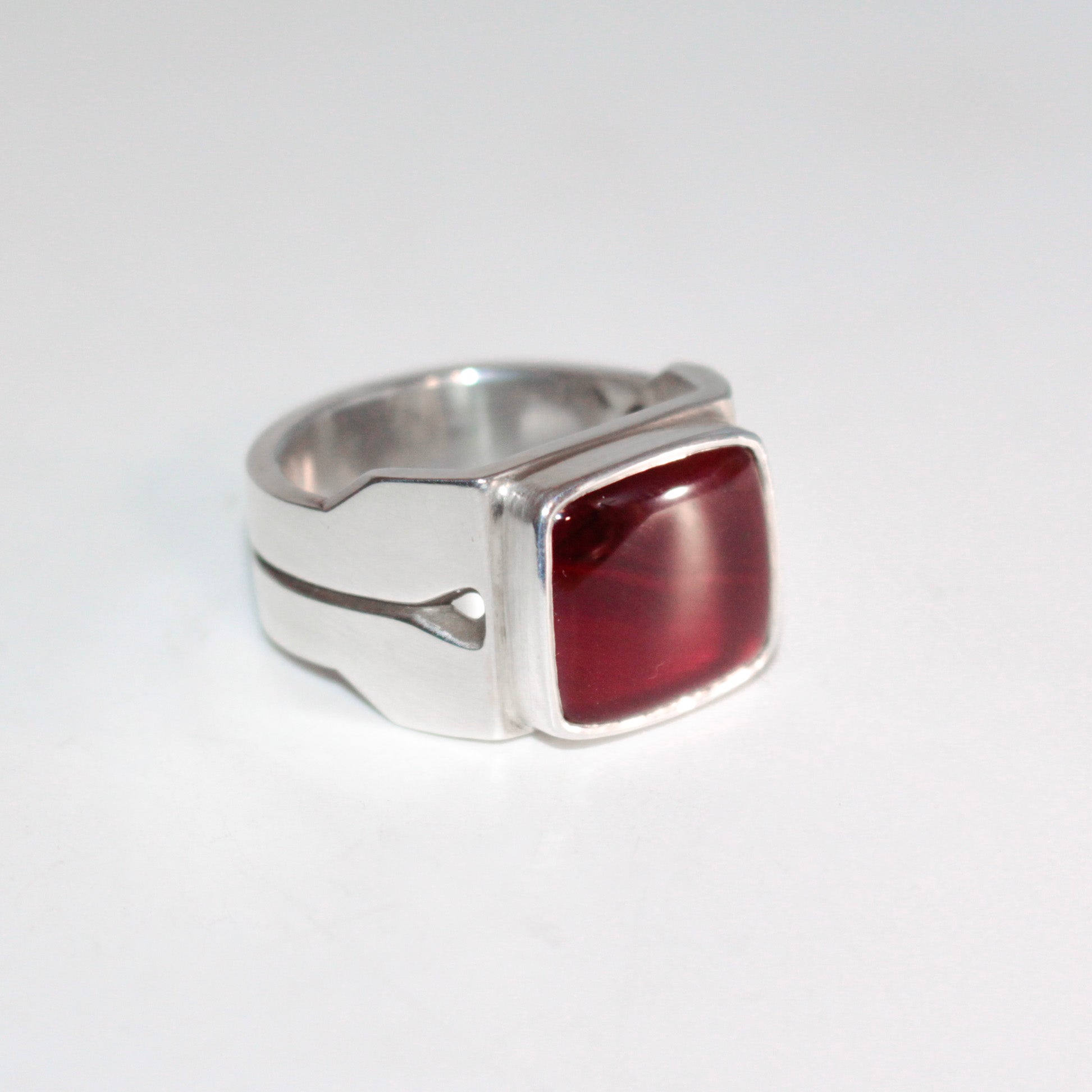 A silver ring with a square, rounded red carnelian, photographed on a plain white background.

