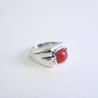 A silver ring featuring a smooth, rounded Red Desert Agate cabochon gemstone, photographed on a plain white background.