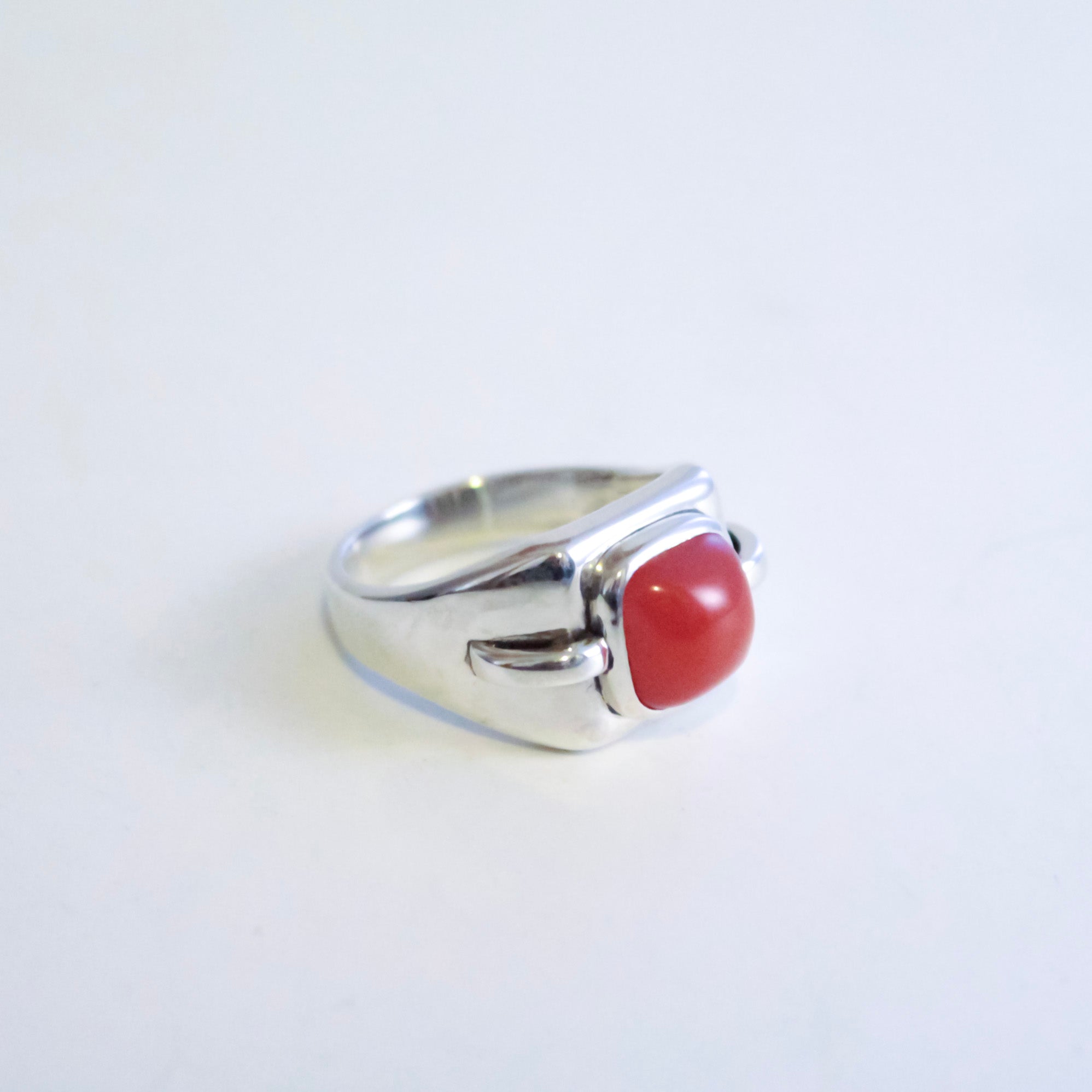 A silver ring featuring a smooth, rounded Red Desert Agate cabochon gemstone, photographed on a plain white background.