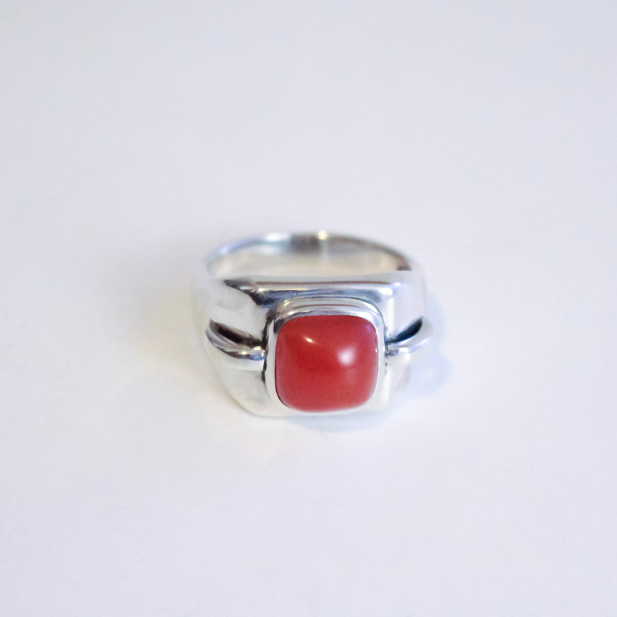 A silver ring featuring a smooth, rounded Red Desert Agate cabochon gemstone, photographed on a plain white background.