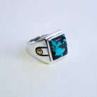 A silver signet ring featuring a square hubei turquoise stone, set against a plain light background.