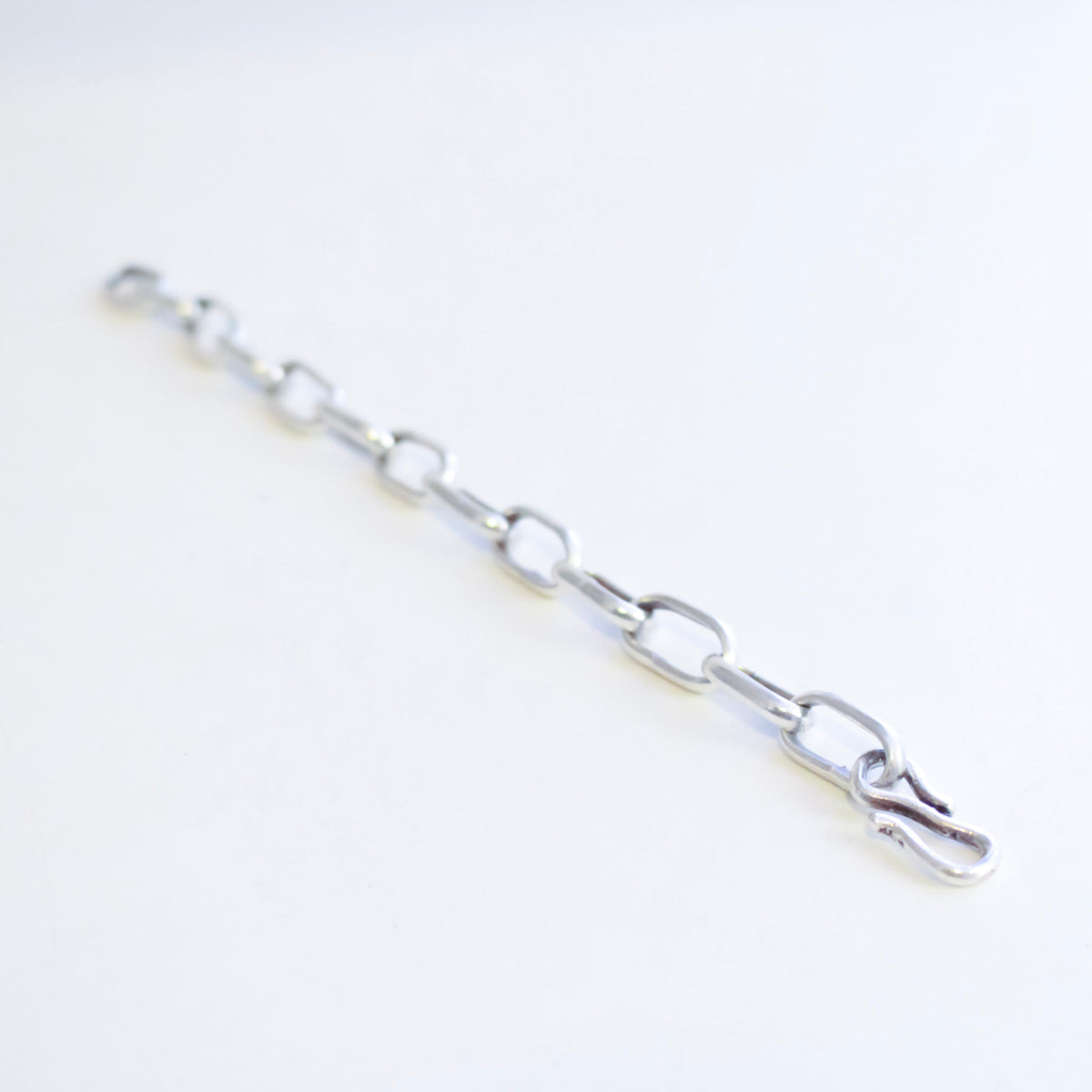 A silver metal link chain with elongated oval links and a hook clasp, photographed on a plain white background.