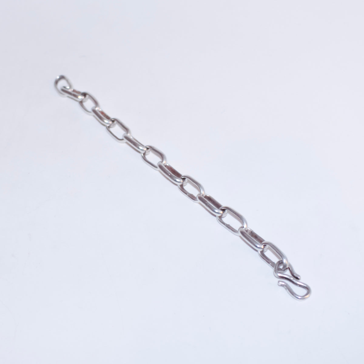 A silver chain link bracelet with elongated oval links and a hook clasp, shown diagonally on a plain white background.