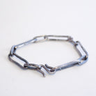 A handmade sterling silver chain link bracelet, featuring a rustic, weathered finish, displayed on a plain white surface.