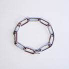 A sterling silver and copper chain bracelet with elongated oval links and a hook clasp, photographed diagonally on a plain white background.