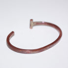 A hammered copper-colored metal cuff bracelet with a T-bar, shown on a plain white background.