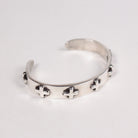A silver open cuff bracelet featuring small raised cross star motifs spaced along the front, photographed on a plain light background.