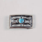 A rectangular sterling silver belt buckle featuring a central oval turquoise stone surrounded by decorative curved silver bars and small bead accents, shown on a plain light gray background.