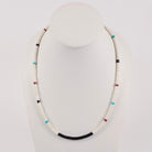 A beaded necklace displayed on a white mannequin bust against a light gray background. The necklace consists of predominantly white beads with small accent beads in turquoise blue, black, red, and white.