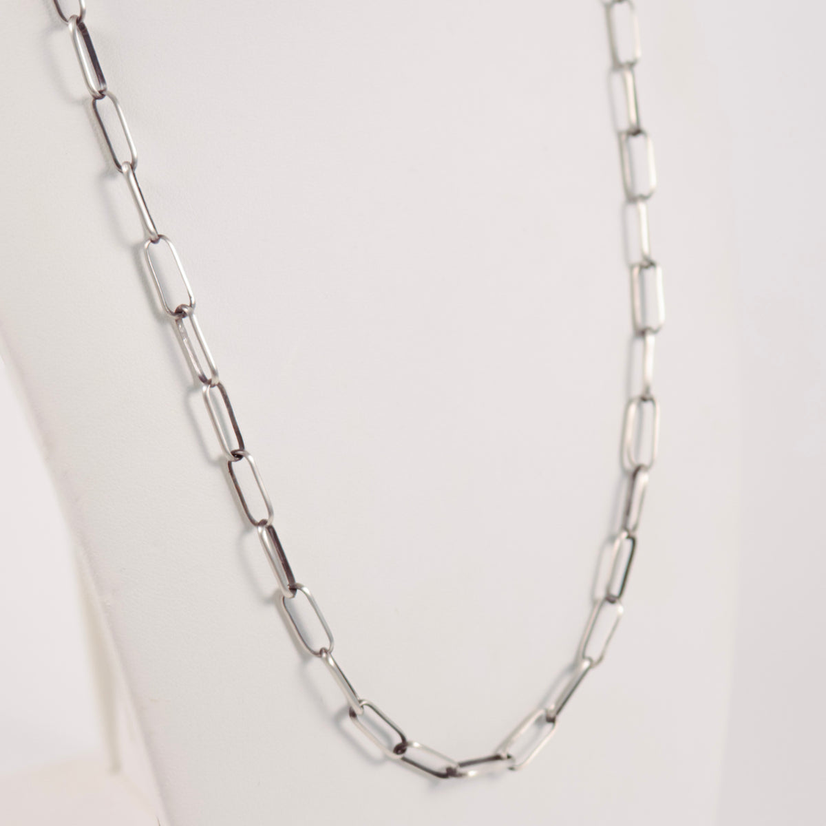 A handmade sterling silver paperclip link chain necklace displayed on a white mannequin bust against a light gray background.