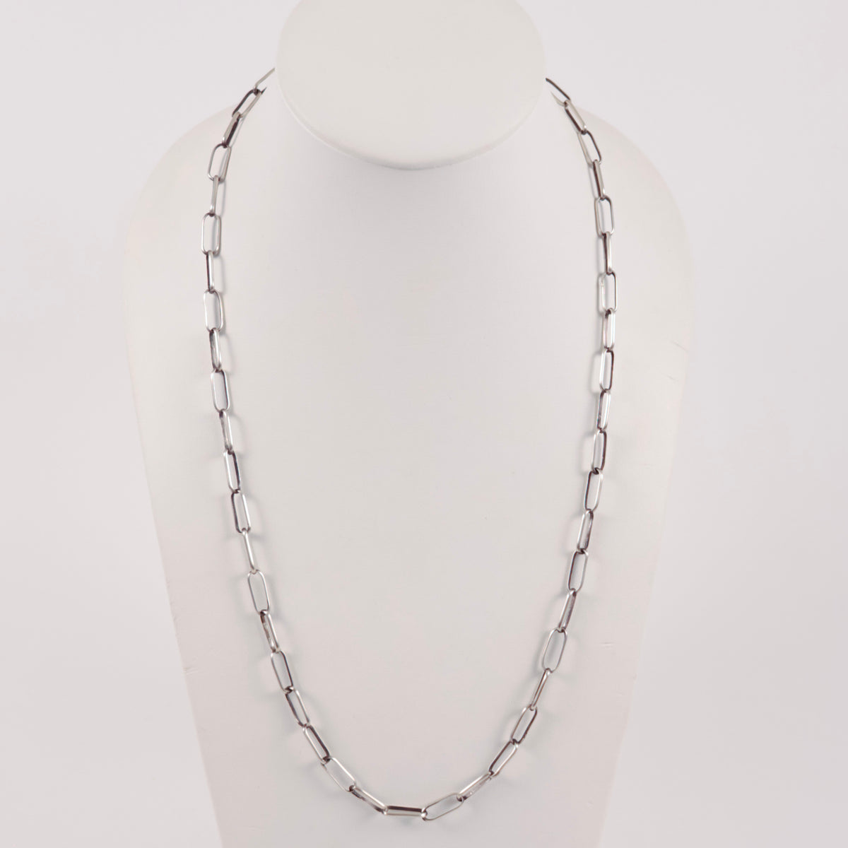 A handmade sterling silver paperclip link chain necklace displayed on a white mannequin bust against a light gray background.